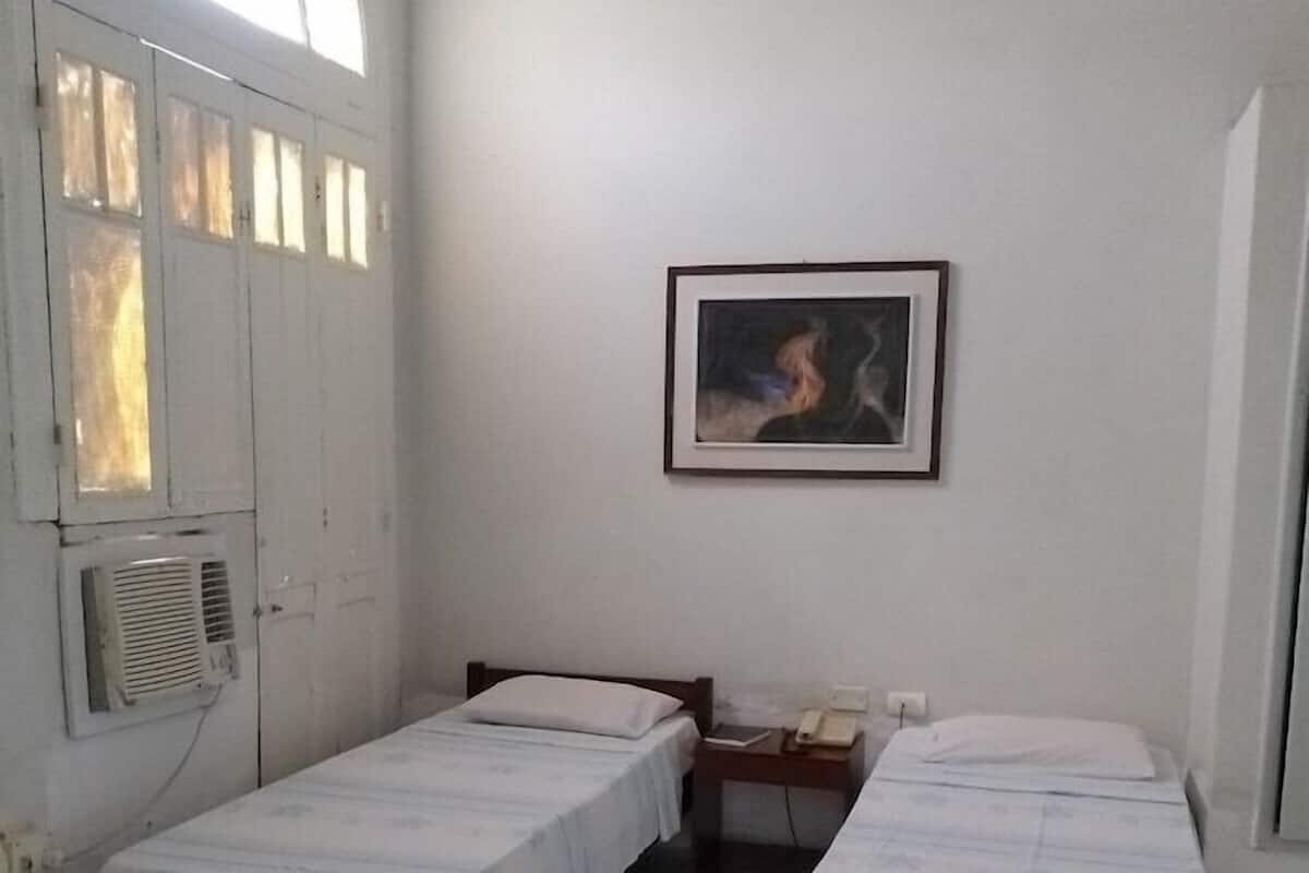 A room with two single beds, a chair, a desk, and a window with a view.