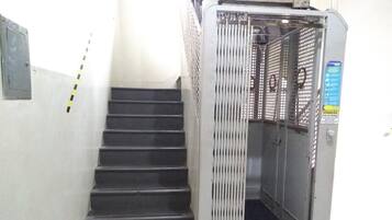 Un escalier avec une porte métallique d’ascenseur et une main courante.