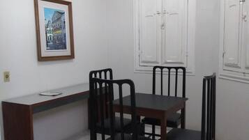 A dining area with a table and four chairs, a small desk, and a framed picture on the wall.