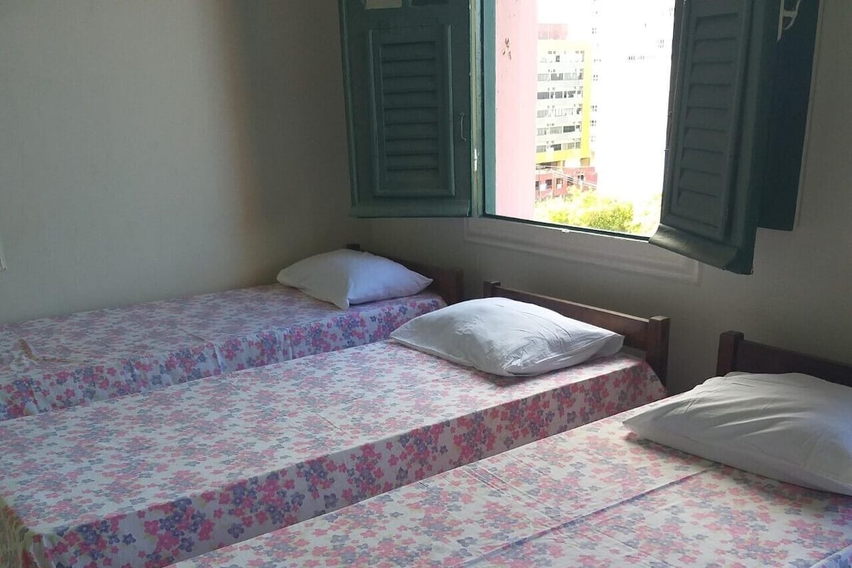 A room with two single beds, each with a floral bedspread and white pillows.