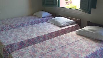 Een kamer met twee eenpersoonsbedden, elk met een bloemenprint sprei en witte kussens.