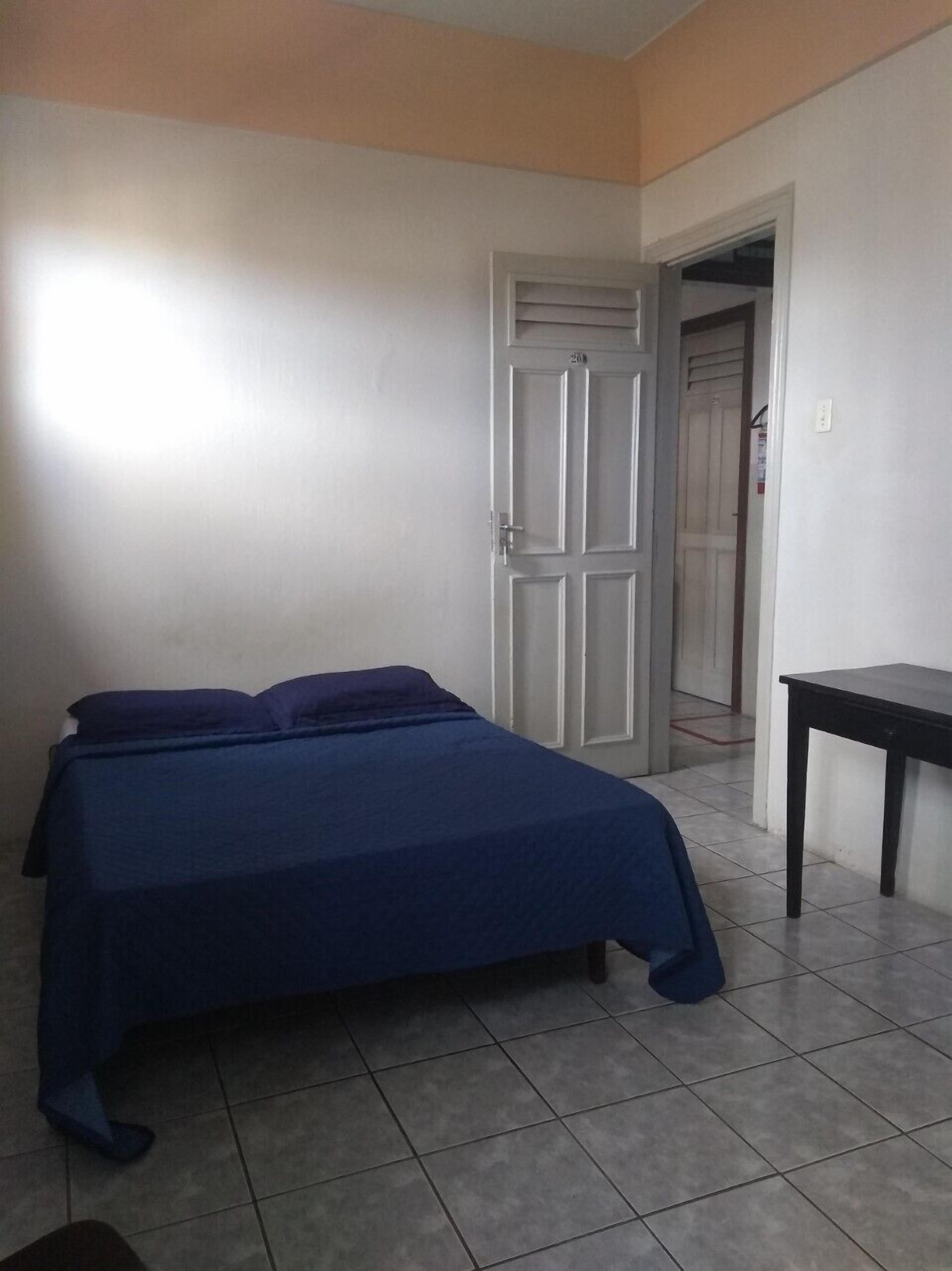 Un dormitorio con una cama, un escritorio y una puerta que da a otra habitación.