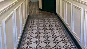 A hallway with patterned flooring and a green door at the end. - Quiet, cozy apartment on flower-filled courtyard in Paris. (Paris)