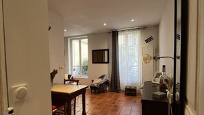 A spacious living area with a dining table, a sofa, and a TV stand. - Quiet, cozy apartment on flower-filled courtyard in Paris. (Paris)