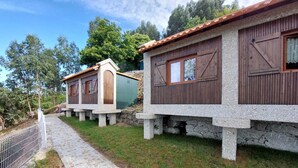 Una hilera de cabañas rústicas con cimientos de piedra y exteriores de madera, unidas por un sendero pavimentado.