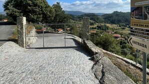 Un sendero de piedra que lleva a una entrada con portón, con un cartel que indica opciones de alojamiento y direcciones.