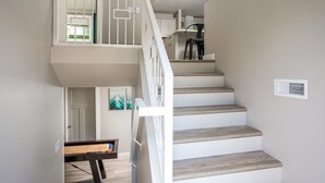 Ein mehrgeschossiges Interieur mit einer Treppe, einem Essbereich und einer Tür zu einem weiteren Raum.