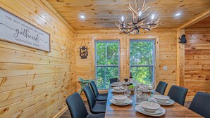 Una sala da pranzo in legno con un tavolo grande apparecchiato per sei persone, circondato da sedie nere.