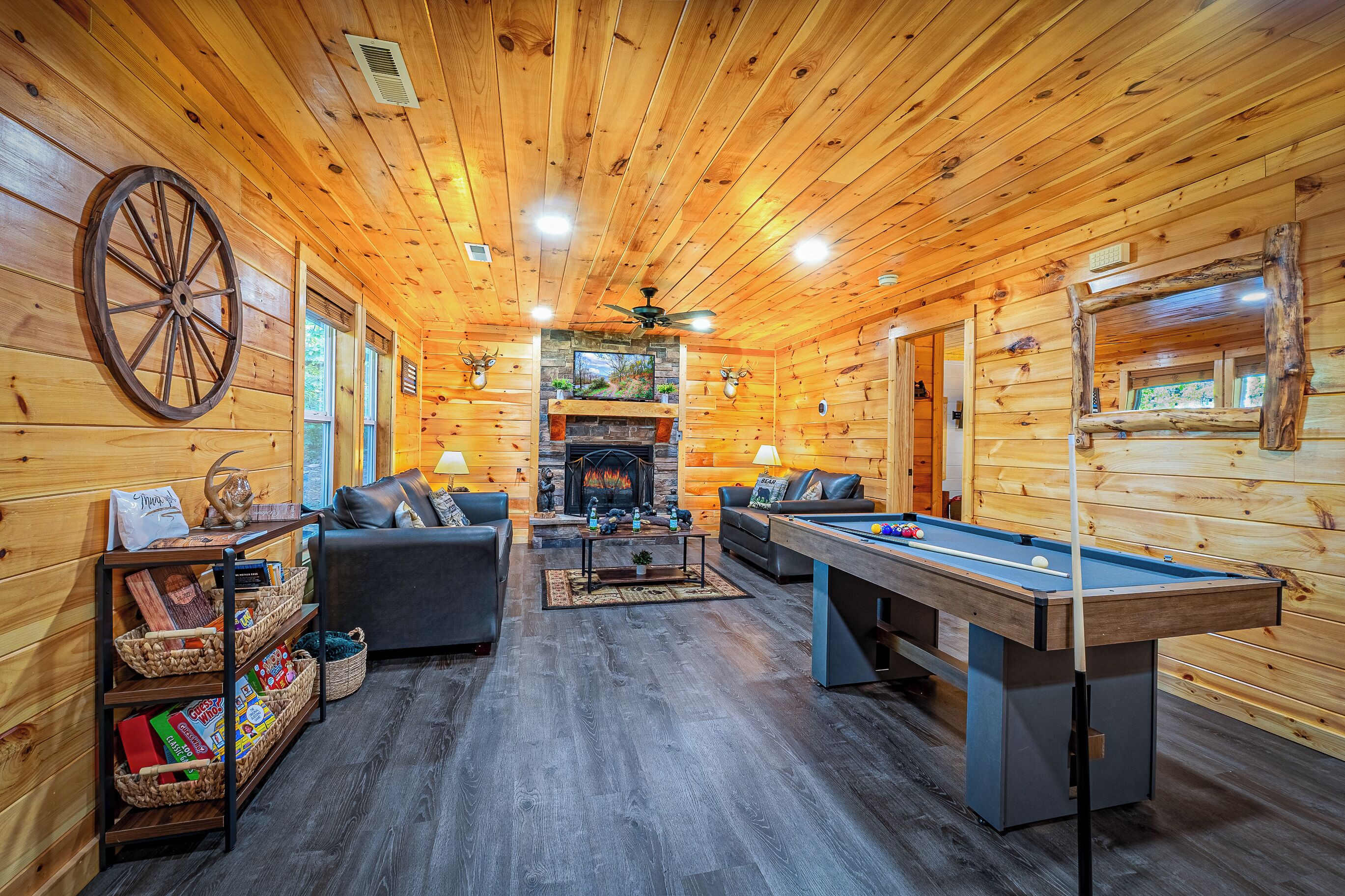 A cozy log cabin interior with a fireplace, pool table, and comfortable seating.