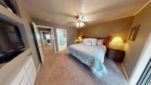 A bedroom with a bed, ceiling fan, bedside lamps, and a TV mounted on the wall. - Walk to Lifts | Wooded Area | Rustic Interior | French Henry B2 (Angel Fire)