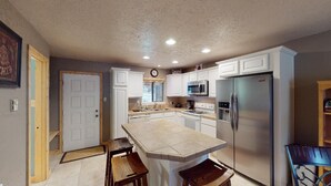 A kitchen with white cabinets, a stainless steel refrigerator, a microwave, and a sink. - Walk to Lifts | Wooded Area | Rustic Interior | French Henry B2 (Angel Fire)