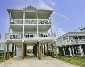 A two-story building with a balcony on the upper floor, supported by wooden stilts. - Kalm by the Beach - Ocean View - Sleeps 14 (Surfside Beach)