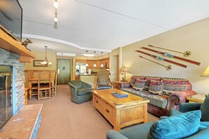 Relax in a cozy living room with a fireplace, sofa, armchairs, and dining area.