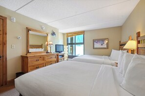 Two single beds with white linens, a dresser, flat-screen TV, and large mirror.