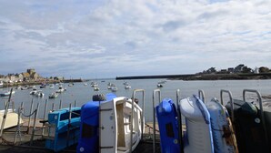 A marina with boats docked, a lighthouse in the distance, and a coastal town with buildings. - La Forge, house for 6 in the heart of Barfleur, with private parking lot (Barfleur)