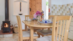 A cozy dining area with a wooden table, chairs, and a built-in wood stove. - 2 bedroom accommodation in Narberth (Narberth)