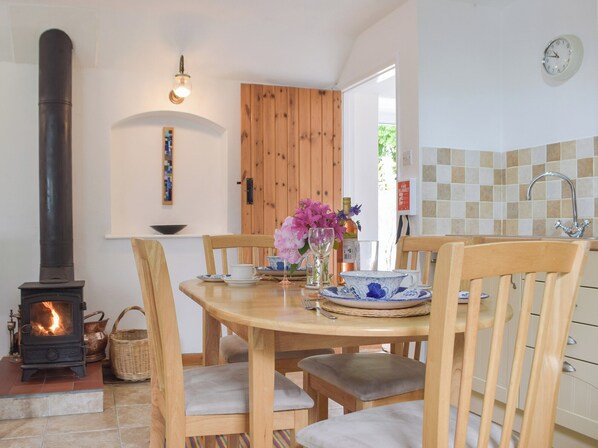 A cozy dining area with a wooden table, chairs, and a built-in wood stove. - 2 bedroom accommodation in Narberth (Narberth)
