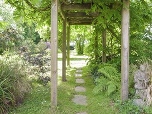 A garden pathway under a wooden pergola with stone steps, surrounded by lush greenery and ferns. - 2 bedroom accommodation in Narberth (Narberth)