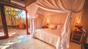 Ein Schlafzimmer mit Baldachinbett, Holzboden und Blick auf Bambus.