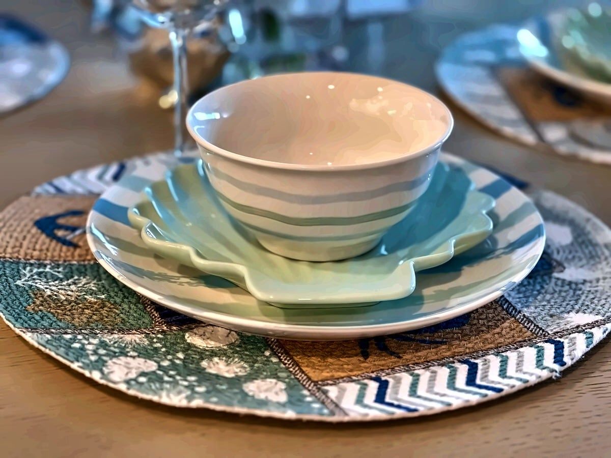 Una mesa dispuesta con un plato y un posavasos sobre un mantel individual estampado.