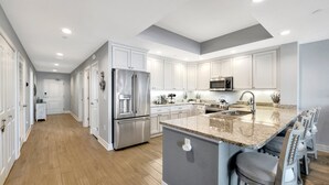 Una cocina moderna con armarios blancos, electrodomésticos de acero inoxidable y encimera de granito.
