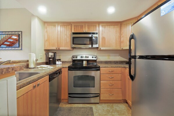 Kitchen features a stove, refrigerator, microwave, and dishwasher, with a sink and granite countertop.