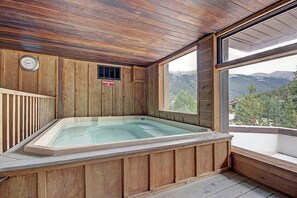 Relax in a serene spa room with a hot tub, mountain views, and a cozy bench.