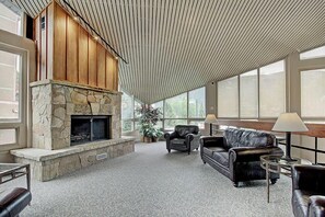 Cozy living area with a fireplace, leather sofas, and high ceiling.