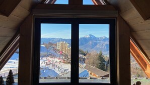 A room with a large window offering a view of a ski resort and mountains. - B306 - 79 m2 - 4P - 8 pers (Prapoutel)