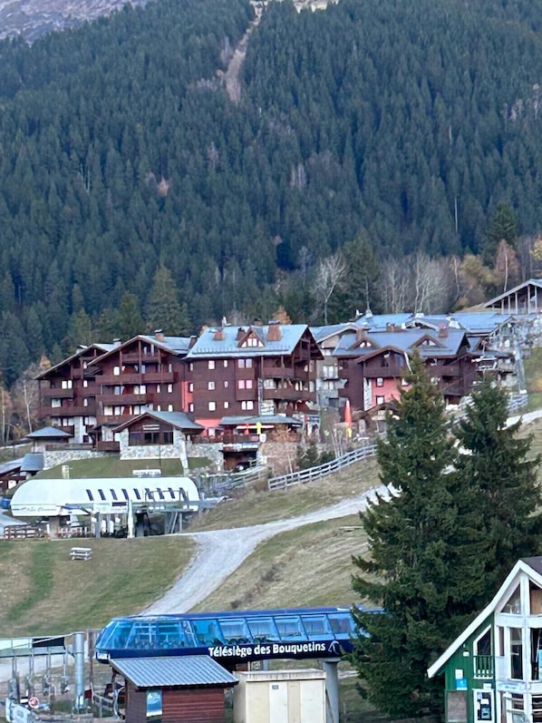 A mountain lodge with multiple wooden buildings, a ski lift, and a sign reading "Téléslège des Bouquetsins".