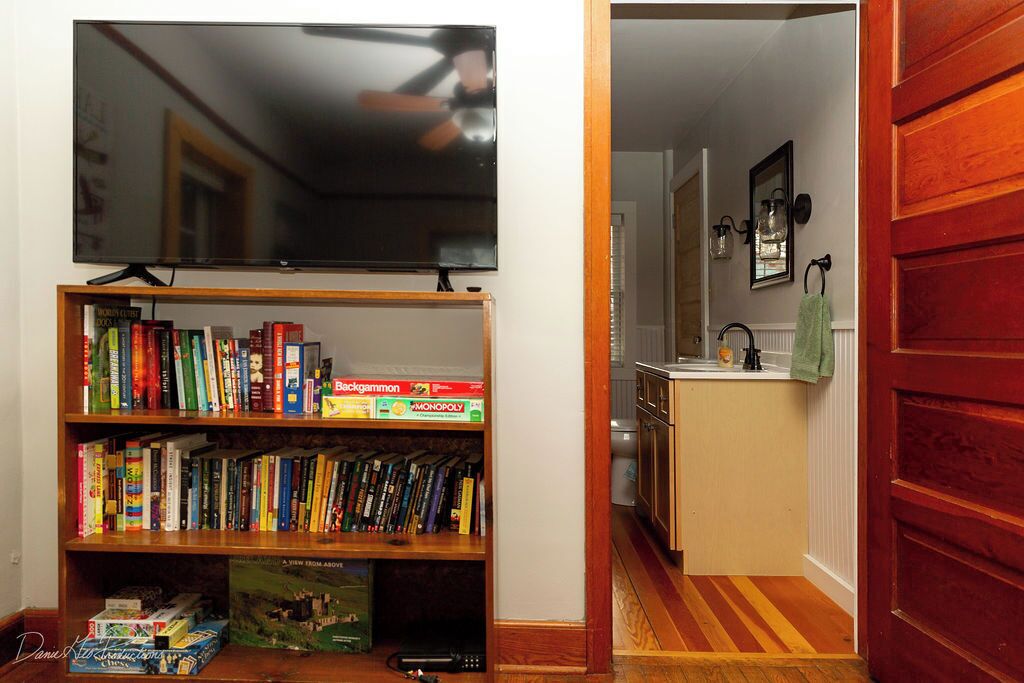 A living room with a bookshelf, a television, and a kitchen area.