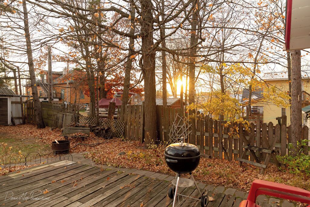 Una terraza de madera con una parrilla y una silla roja.