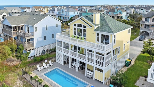 Una casa de varios pisos con piscina, balcones y vistas al océano.