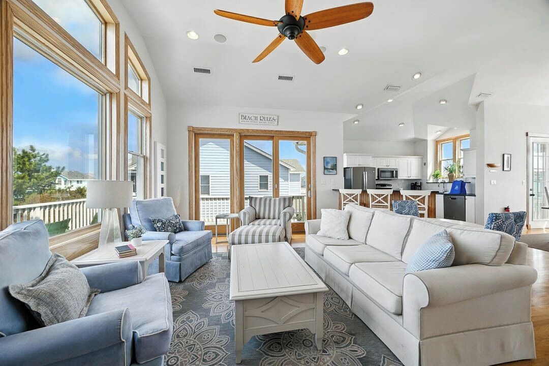 A spacious living area with a large window, a ceiling fan, and a view of the outside.