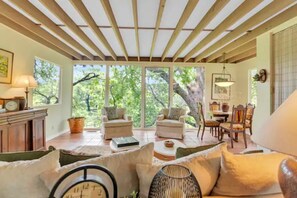 A spacious living area with a wooden ceiling, large windows, and a dining area with wooden furniture. - New!!! Luxury Riverfront Oasis with Gorgeous Oaks and Ping Pong Table! (Seguin)