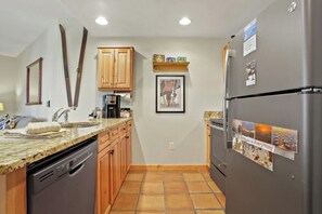 Kitchen features a granite countertop, wooden cabinets, and a stainless steel refrigerator.