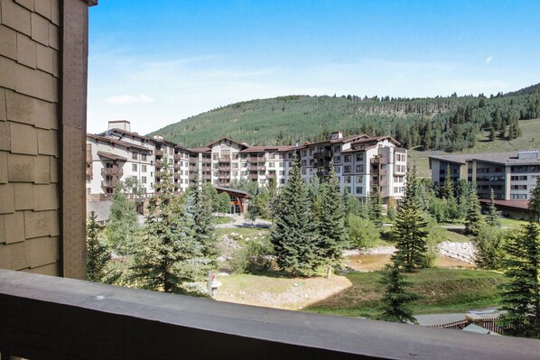 Guests can enjoy scenic views from the hotel's balconies overlooking a serene natural landscape with trees and a small stream.