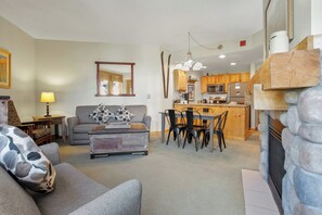 Relax in this inviting space with a sofa, coffee table, and dining table, surrounded by a fireplace and kitchen amenities.