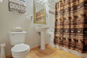 Bathroom features a pedestal sink, shower area, and toilet, with a patterned shower curtain.