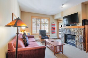 Relax by the fireplace in this inviting living room, featuring a comfortable sofa, floor lamp, and mounted TV.