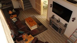 Una sala de estar con un sofá de cuero marrón, una mesa de centro de madera y un televisor de pantalla plana montado en la pared.