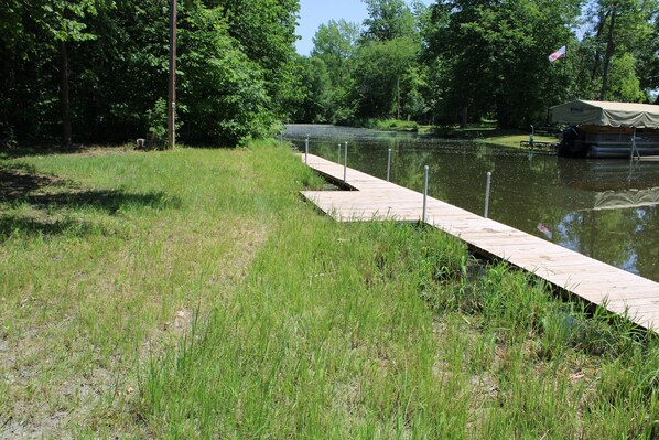 A wooden dock extending into a calm body of water, surrounded by lush greenery and trees.