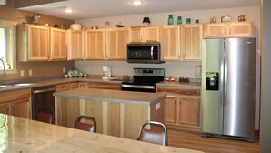 Una cocina moderna con armarios de madera, electrodomésticos de acero inoxidable y encimera de granito.