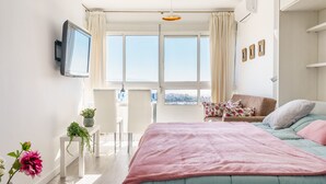 Una camera moderna con un letto grande, una TV a parete e un balcone con vista.