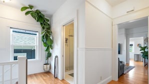 Ein Flur mit Holzboden, weißen Wänden und einer großen Pflanze im Blumentopf.