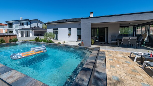 Uma casa moderna com piscina, área de estar externa e um pátio.
