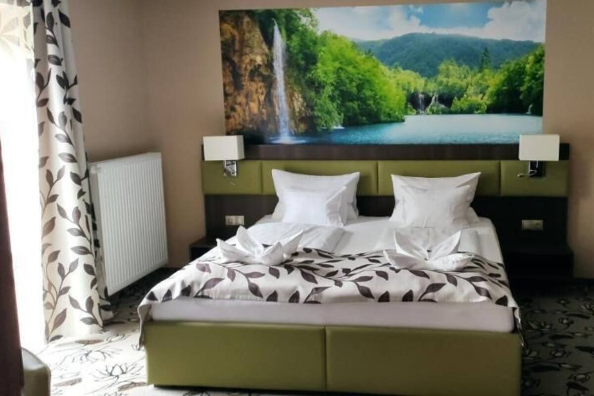 Hotellihuone, jossa on sänky, vesiputousta esittävä taulu ja patteri.