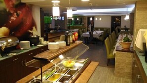 Un espace buffet proposant différents stands de nourriture, un bar et des tables pour s’asseoir.