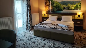 Une chambre d’hôtel avec un grand lit, une vue sur une cascade et une moquette à motifs floraux.