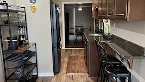 A kitchen with wooden flooring, a refrigerator, a sink, and a dining area with chairs. - Gulfcrest Townhomes Unit 3 (Destin)